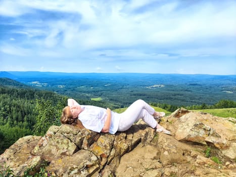 A blogger happily takes a selfie with breathtaking mountain views in the background while enjoying her adventure in nature