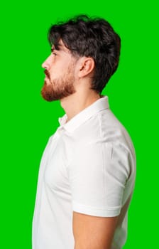 Profile view of a man with a beard wearing a white polo shirt against a bright green background close up