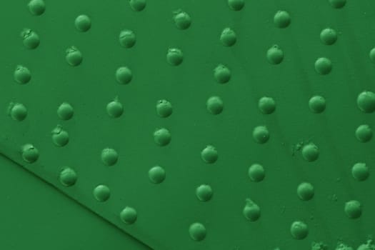 Metal plating with close-up rivets. Military armor of old equipment painted with green paint.