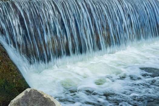 Small waterfall from the river. Cascading waterfall closeup.