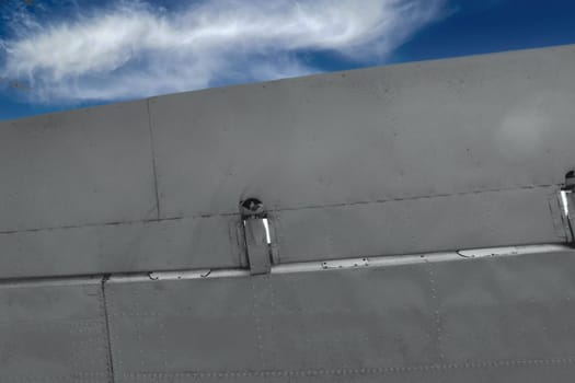 Part of an airplane wing painted green against the sky, view from below.