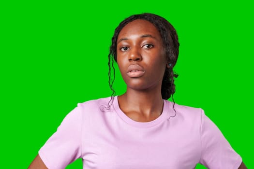 Young woman with an expression of contemplation poses against a bright green background in studio