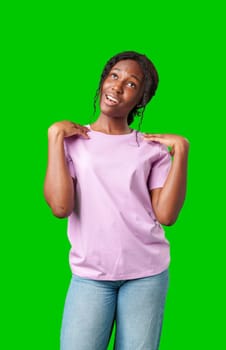 Young woman in casual outfit poses playfully with a surprised expression in front of a bright green backdrop in studio
