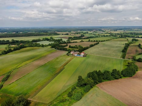 Aerial view of the dark, atmospheric sky over a small Polish village among green fields. High quality photo