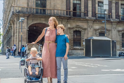 Mother, baby son and teenage son tourists in the central square of Mexico City, Zocalo. Family travel, cultural exploration, and historic architecture concept.