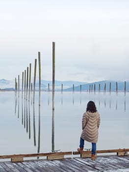 A woman stands at the edge of a dock gazing out at the calm Pend Oreille River on a cold morning in eastern Washington.