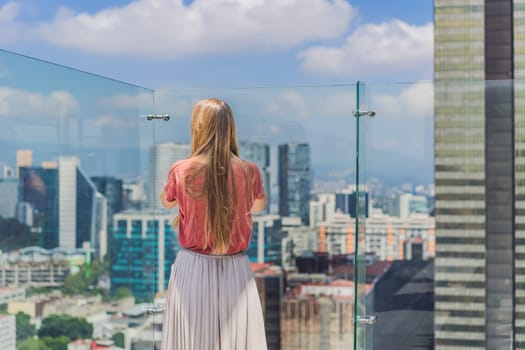 Female tourist or businesswoman standing on a skyscraper rooftop with a panoramic view of Mexico City. Travel or international business in Mexico concept.