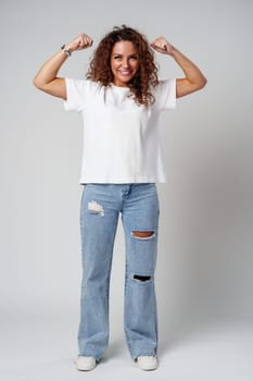 Young woman joyfully celebrates in casual attire against a neutral background close up
