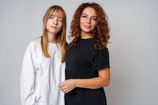 Two women standing together, one in white and the other in black, showcasing a warm connection in studio