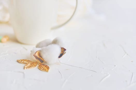 Serene atmosphere with white background, cotton flower, and golden leaves creates a refined setting