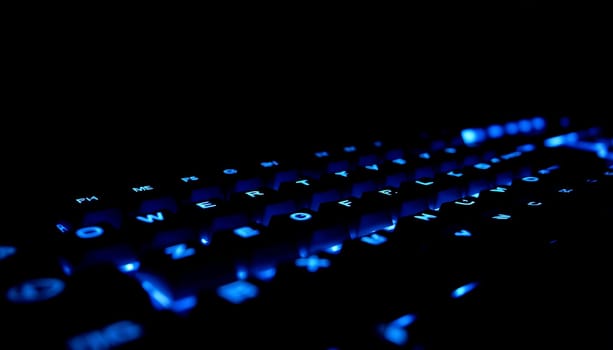 A close up shot of a backlit keyboard with blue lighting. The focus is on the keys, which are glowing brightly, creating a futuristic and modern feel. The image can be used to represent technology, gaming, or modern design. It's a perfect visual for tech-related content or website design. ,