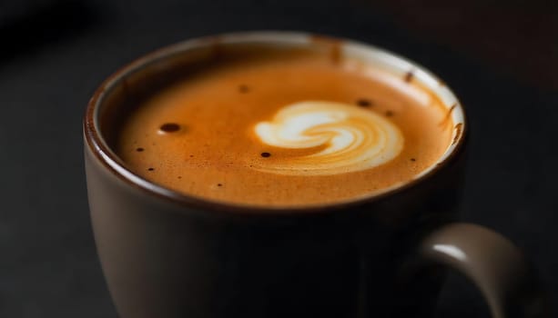 A close-up shot of a cup of coffee with a beautiful swirl of latte art on top. The coffee is dark and rich, and the milk foam is light and creamy. The image is perfect for use in advertising, marketing, or social media. It conveys a sense of indulgence and enjoyment.