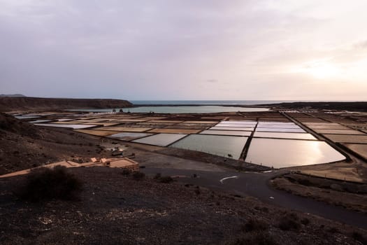 salt flats against lagoon and ocean at sunset in Yaiza, Lanzarote at Canary Islands in Spain, concept of nature and marine lifestyle