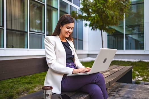 Businesswoman working on laptop outdoors.