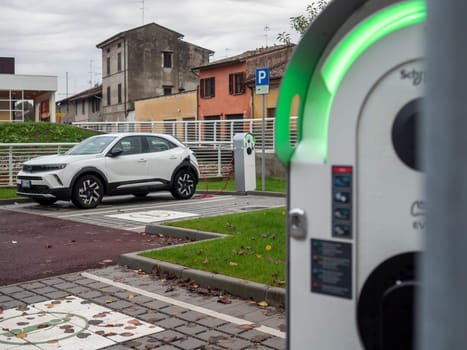Cremona, Lombardy, Italy October 15th 2024 White electric car charging at a public charging station, promoting sustainable transportation and eco friendly practices in an urban environment
