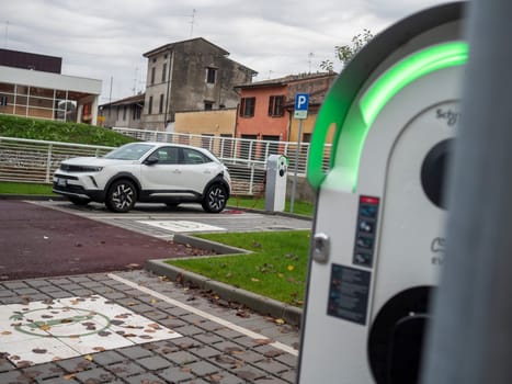 Cremona, Lombardy, Italy October 15th 2024 Modern white electric car charging at a public charging station, promoting sustainable transportation in an urban environment