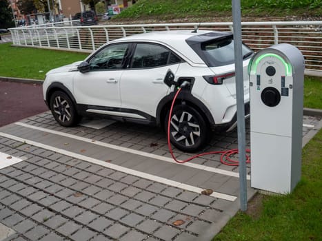 Cremona, Lombardy, Italy October 15th 2024 Modern white electric car charging its battery at a public charging station, promoting sustainable transportation and eco friendly practices