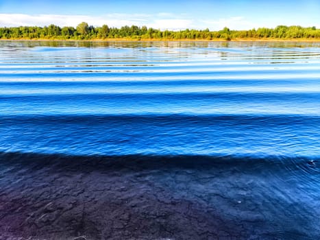 Calm water reflects the blue sky while gentle ripples create patterns along the surface.