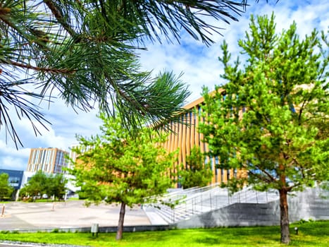 A striking building stands amidst vibrant trees under a clear blue sky, showcasing the harmony of nature and modern design.