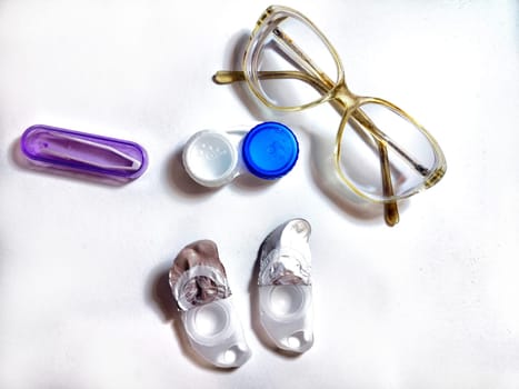 A pair of stylish glasses is placed alongside contact lens case and solution, showcasing daily eyewear essentials for eye care