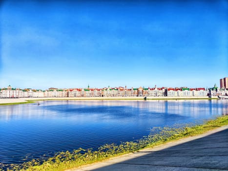 Charming houses line the waterways of Yoshkar-Ola, reflecting in the calm waters on a sunny day.