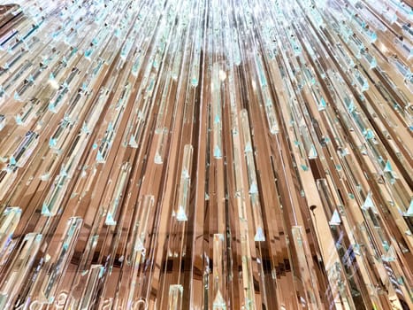 The elegant chandelier glimmers with light as crystal strands descend towards the lobby floor.
