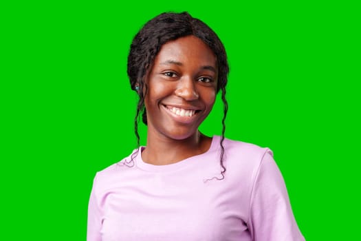 Young woman smiling joyfully in a pink shirt against a vibrant green background in a cheerful atmosphere close up