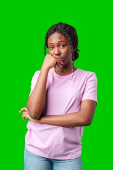 Thoughtful woman pondering in front of a bright green background during a casual moment close up