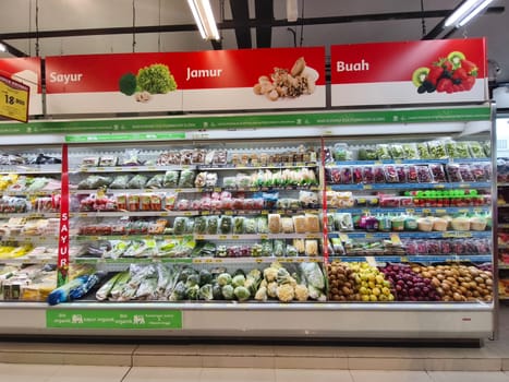A well stocked refrigerated section in a grocery store, showcasing a variety of fresh vegetables, mushrooms, and fruits.