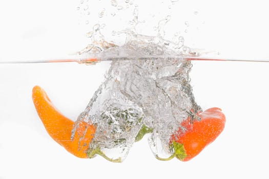 An abstract photo of three sweet peppers dropped into clear water.