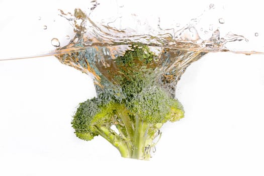 An abstract photo of a head of broccoli being dropped into clear water.