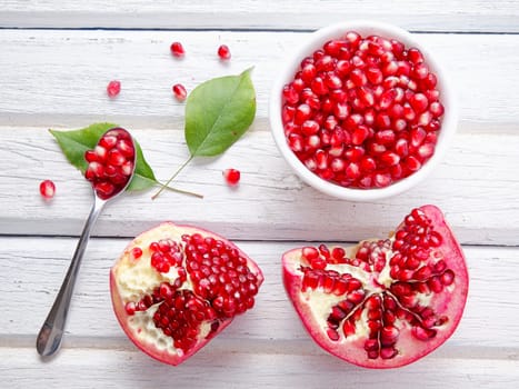 A flatlay food photo of opened pomegranate and a bowl of the seeds.