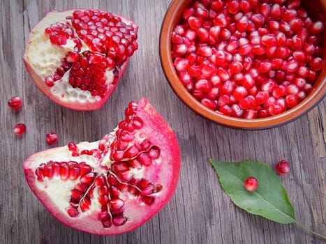 A flatlay food photo of opened pomegranate and a bowl of the seeds.