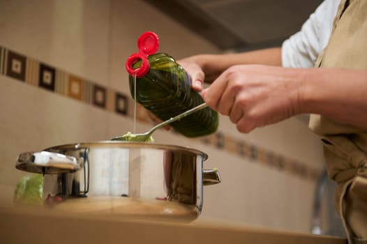 A close-up view of a person pouring oil into a cooking pot, highlighting the preparation of a meal in a kitchen setting. The scene emphasizes home cooking and culinary skills.