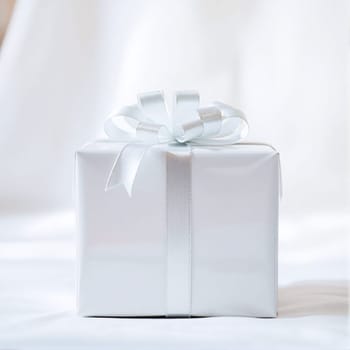 The white gift box sits elegantly on a smooth surface, adorned with a ribbon bow, creating a serene and inviting atmosphere. Perfect for celebrations and special occasions.