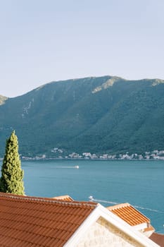 View over the red roofs of houses to a boat sailing on the sea. High quality photo