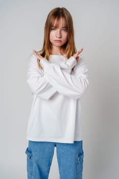 Young woman with long hair confidently poses with crossed arms against a plain background in casual attire