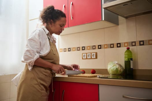 A woman confidently chops vegetables in a modern kitchen, focusing on preparing a nutritious meal. The scene exudes warmth and culinary passion.