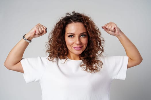 Young woman joyfully celebrates in casual attire against a neutral background close up