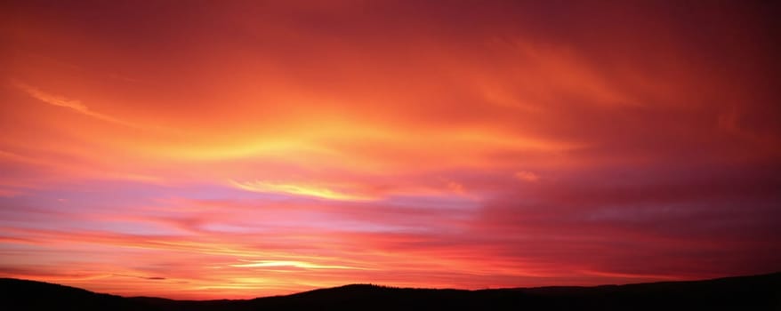 The sky is filled with stunning orange and purple hues as the sun sets behind the hills, creating a breathtaking view that captures the beauty of nature at dusk.