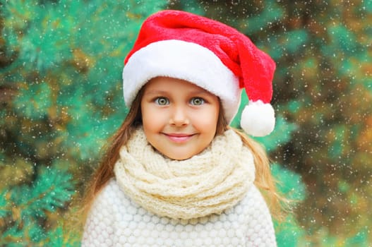 Christmas portrait happy smiling child little girl in santa red hat over tree