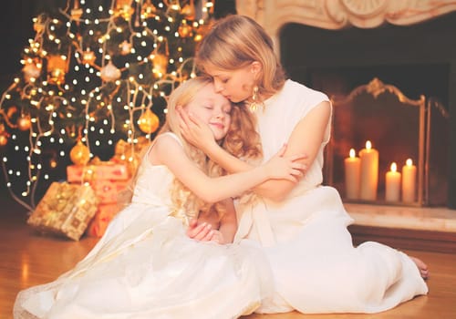 happy mother and child near christmas tree and fireplace at home