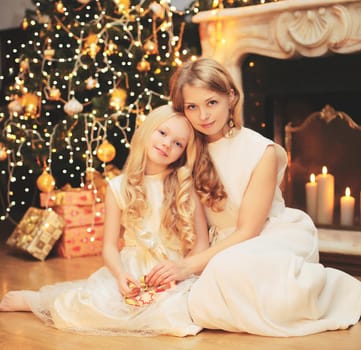Happy mother and child near christmas tree with fireplace at home