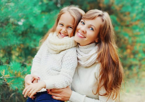 Happy smiling little girl child and mother in winter day over tree