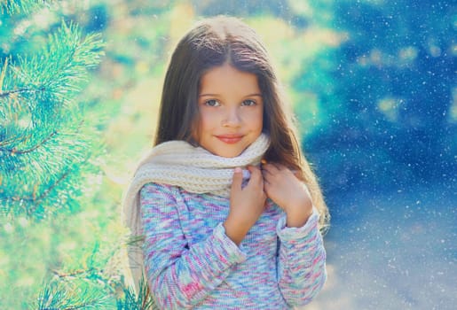 Portrait child little girl in sweater and scarf near branch a tree 