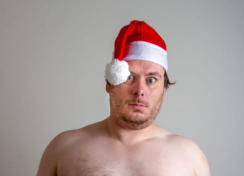 A shirtless man wearing a Santa hat and expressing surprise, conveying humor and quirky holiday spirit. Ideal for unique and funny Christmas themes in seasonal designs.