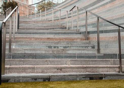 London, UK - Oct 13, 2023 - Perspective view of outdoor steps different coloured with stainless steel sleek railings handle grip. Geometric shape of concrete staircase, Interesting architectural elements, Space for text, Selective focus.