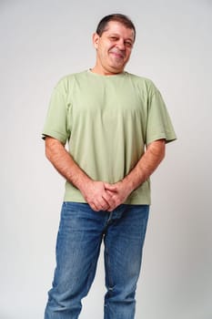 Friendly older man smiling warmly in a light green shirt against a neutral background close up