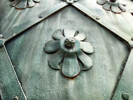 An intricate metal panel showcases floral patterns and textures, reflecting urban artistry and craftsmanship from a close perspective.