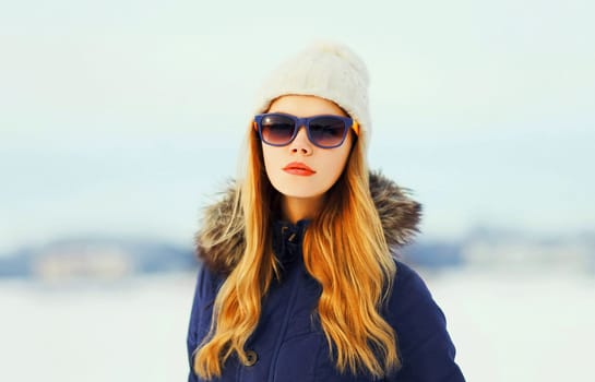 Fashion winter portrait pretty blonde woman wearing a jacket hat and sunglasses 